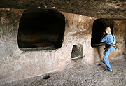 Turista si prohlíží ve skále vytesané hroby Necropoli dell Monte Essu
